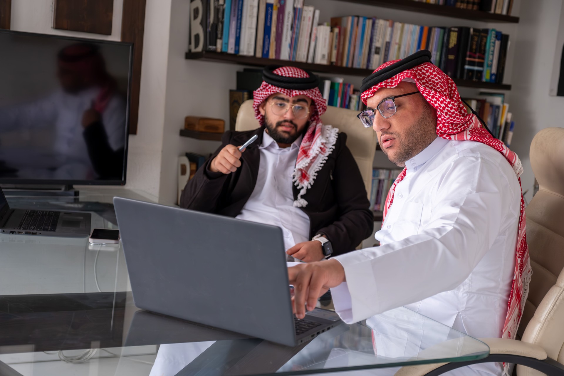 arabic males working on project using laptop and papers while talking and checking all possibilities to enhance outcomes